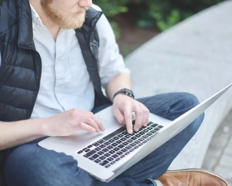 a man sitting on a stone bench using a laptop