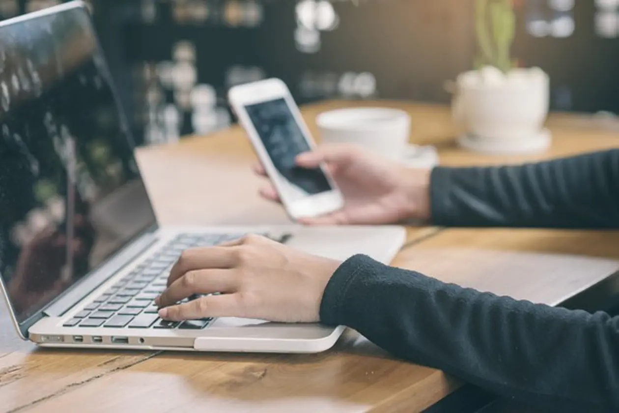 a person using a laptop and a phone