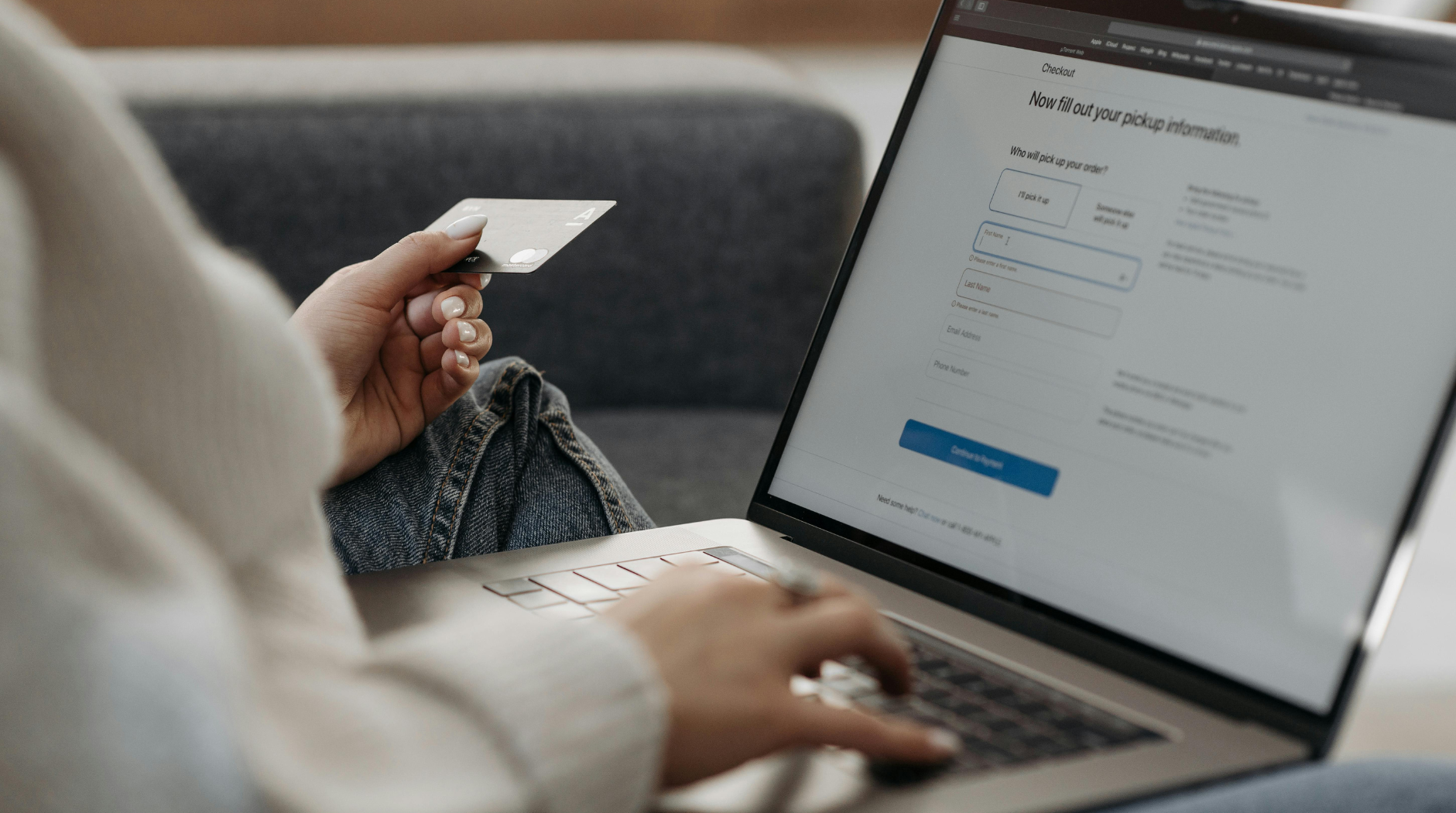 a person holding a credit card and typing on a laptop