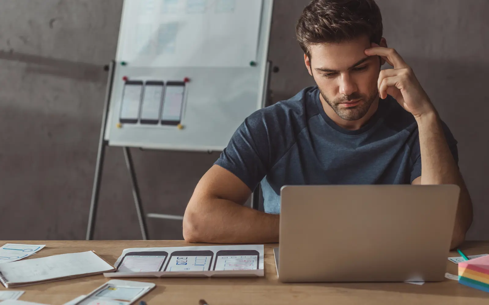 a man sitting at a desk looking at a laptop