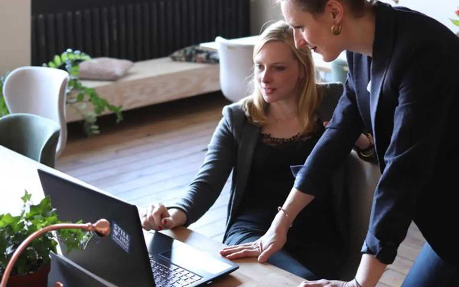 a couple of women looking at a laptop