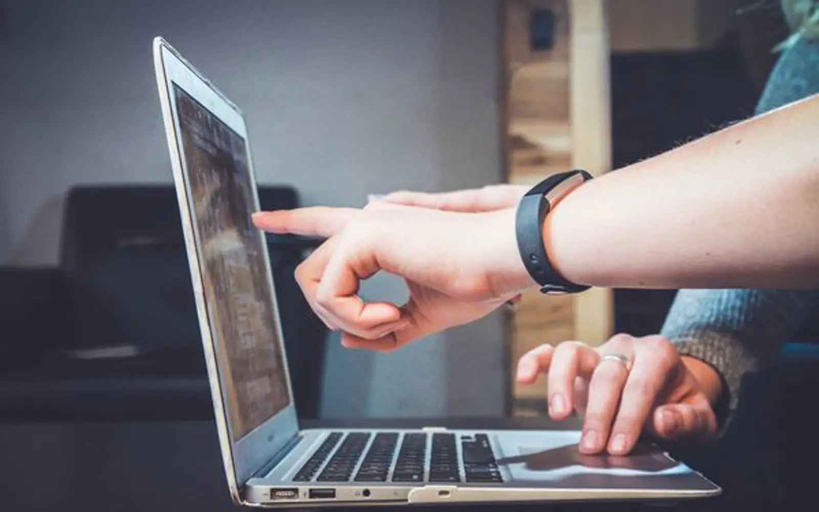 a person pointing at a laptop