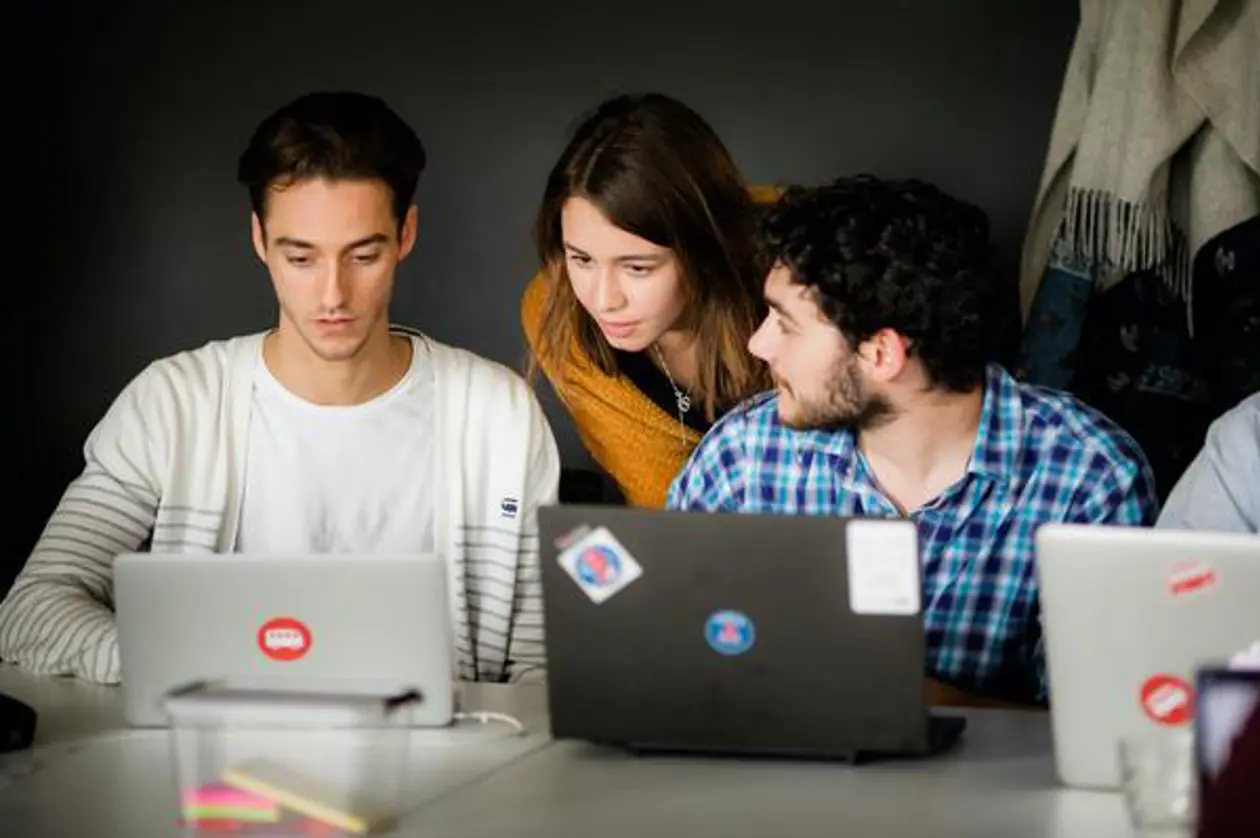 a group of people looking at a laptop