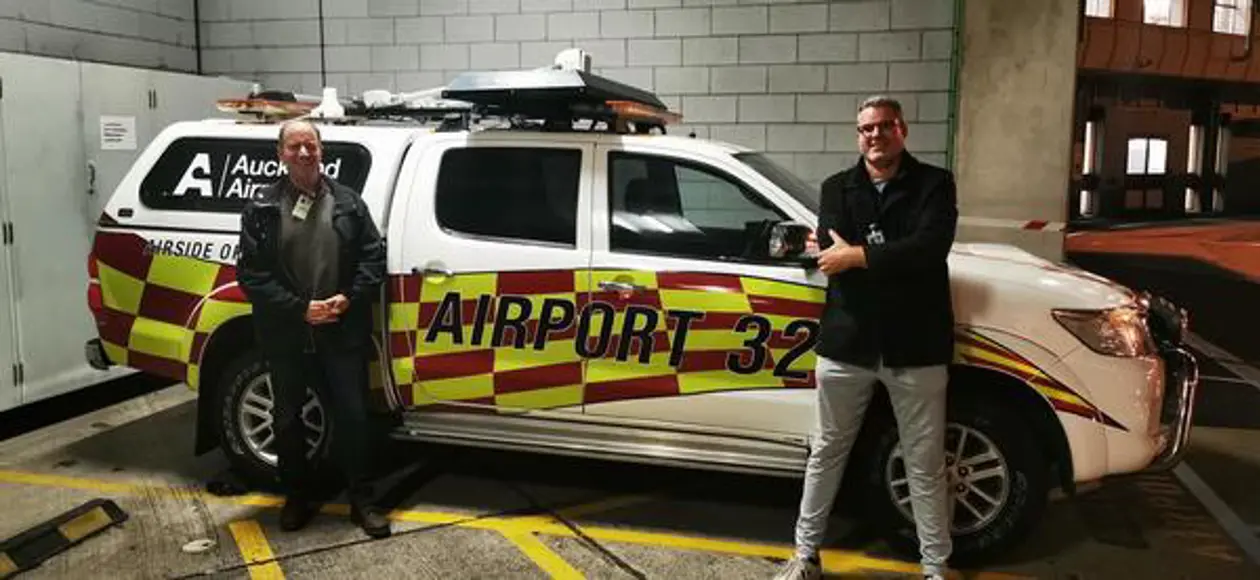 a couple of men standing next to a white vehicle