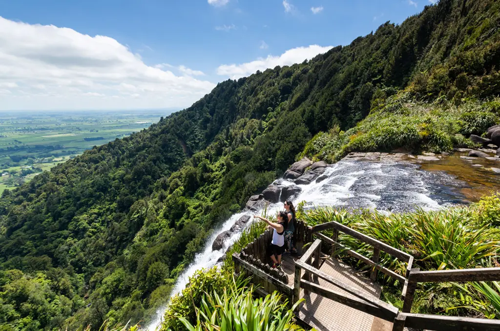 a couple of people standing on a wooden deck overlooking a waterfall