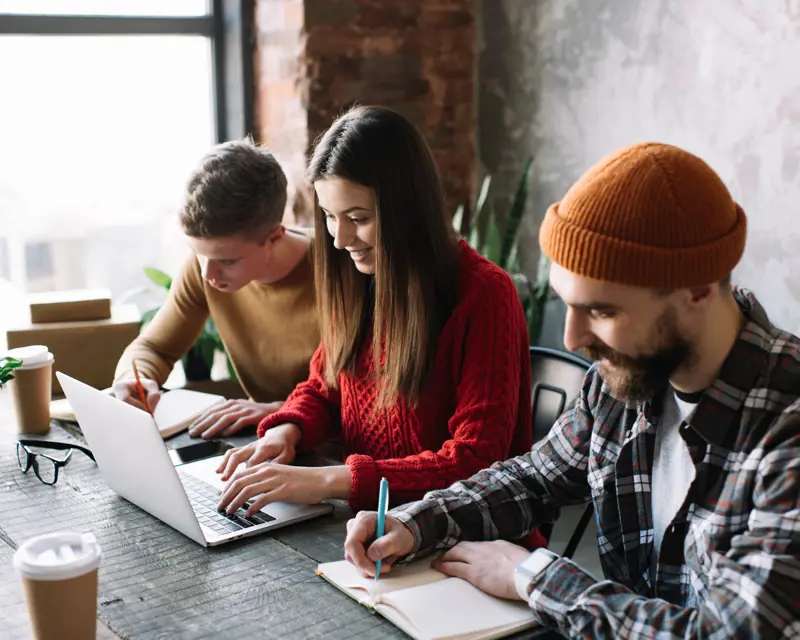 a group of people sitting at a table using a laptop