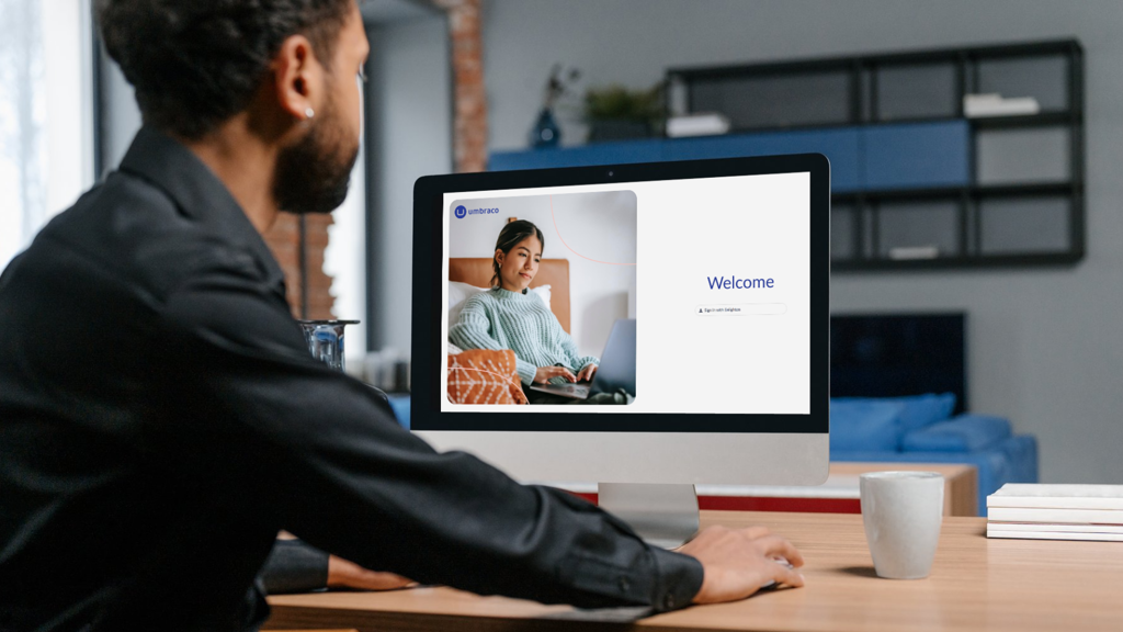 A man looking at a computer screen of Umbraco a Customer Management system.