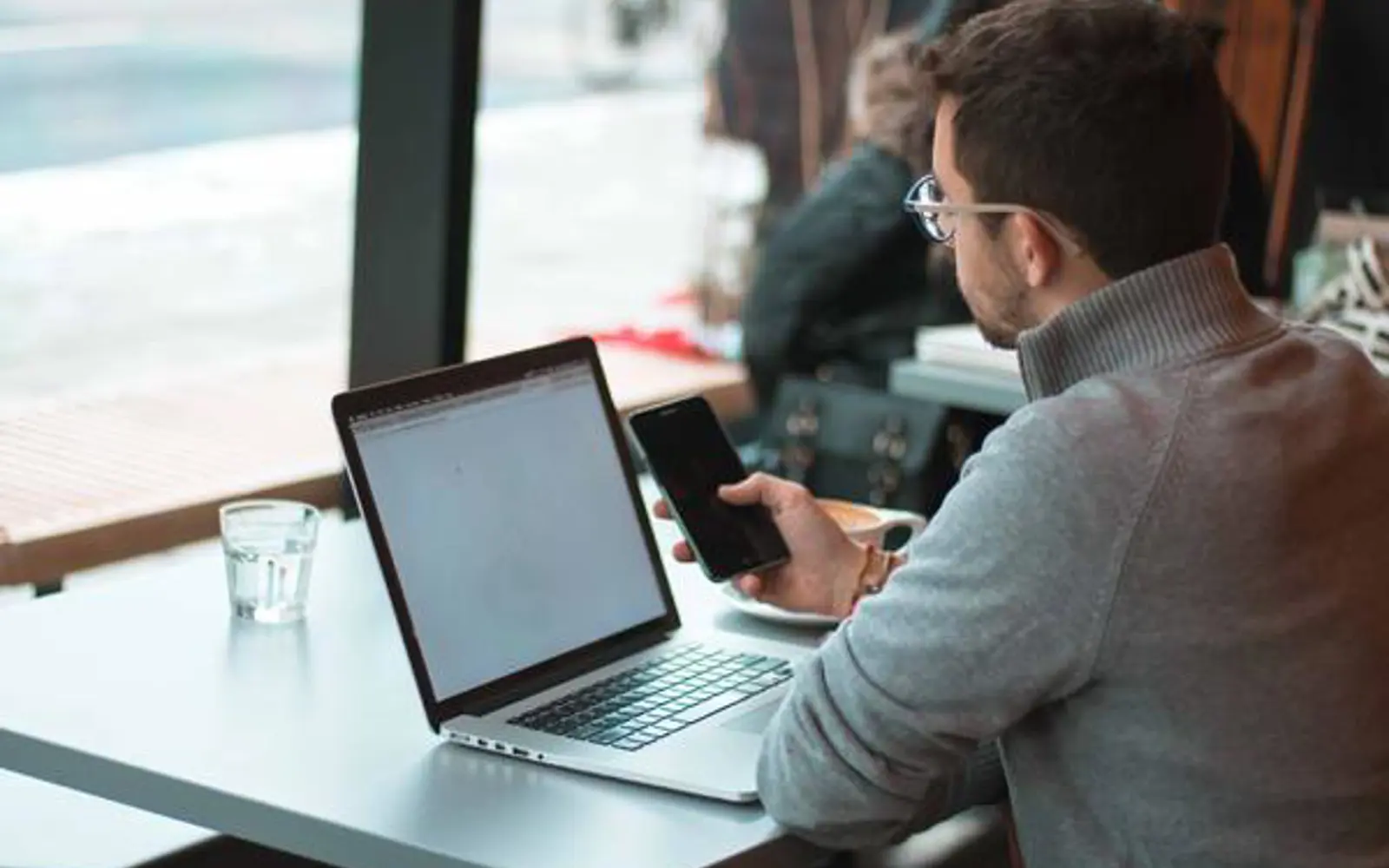 a man sitting at a table with a laptop and a phone