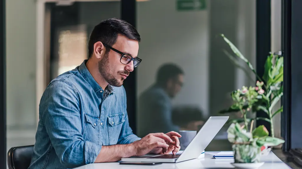 a man sitting at a desk using a laptop