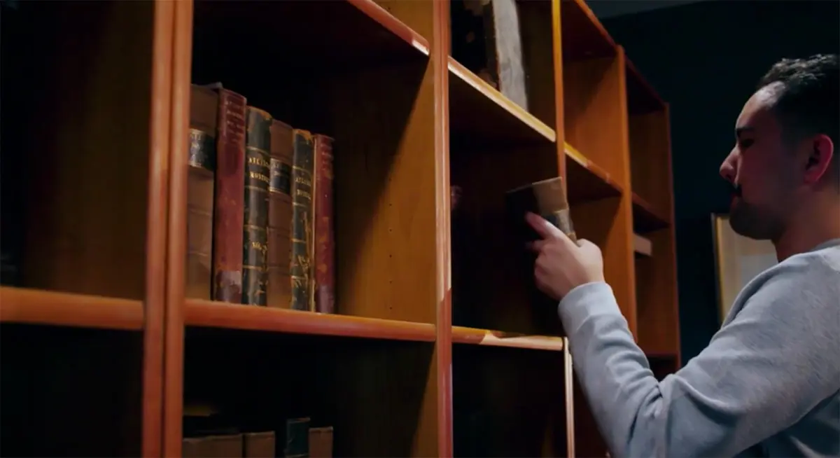 a person touching a book on a shelf