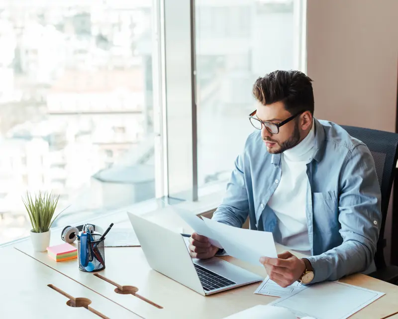 a man sitting at a desk with a laptop and papers