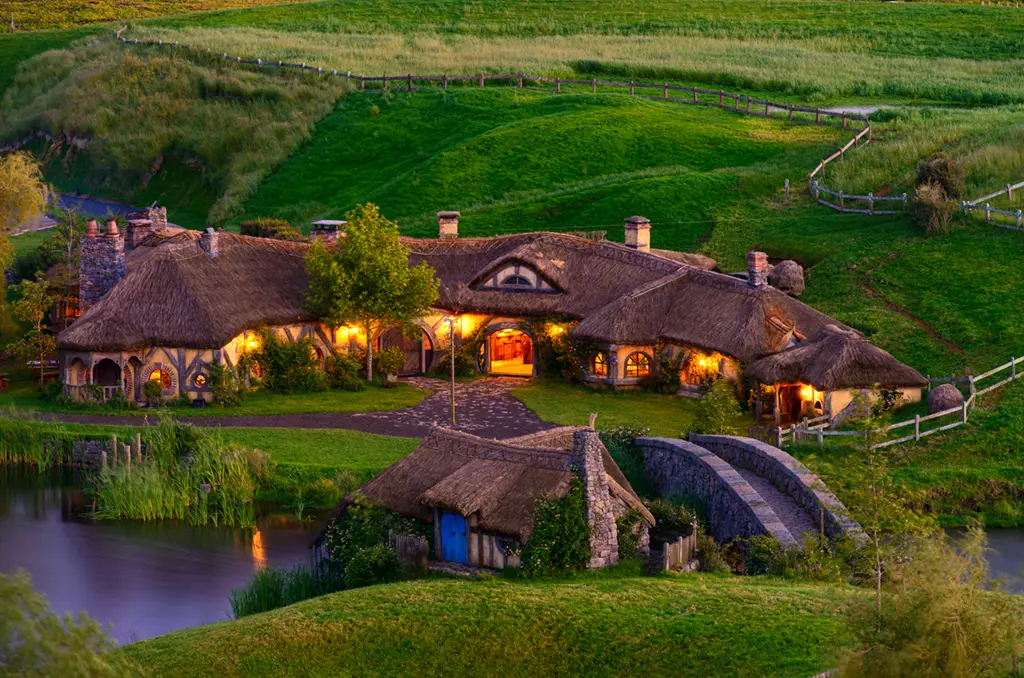 a house with thatched roof and a bridge over water