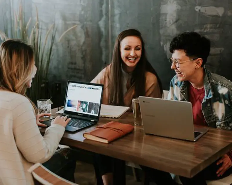 People at a table laughing around laptops.