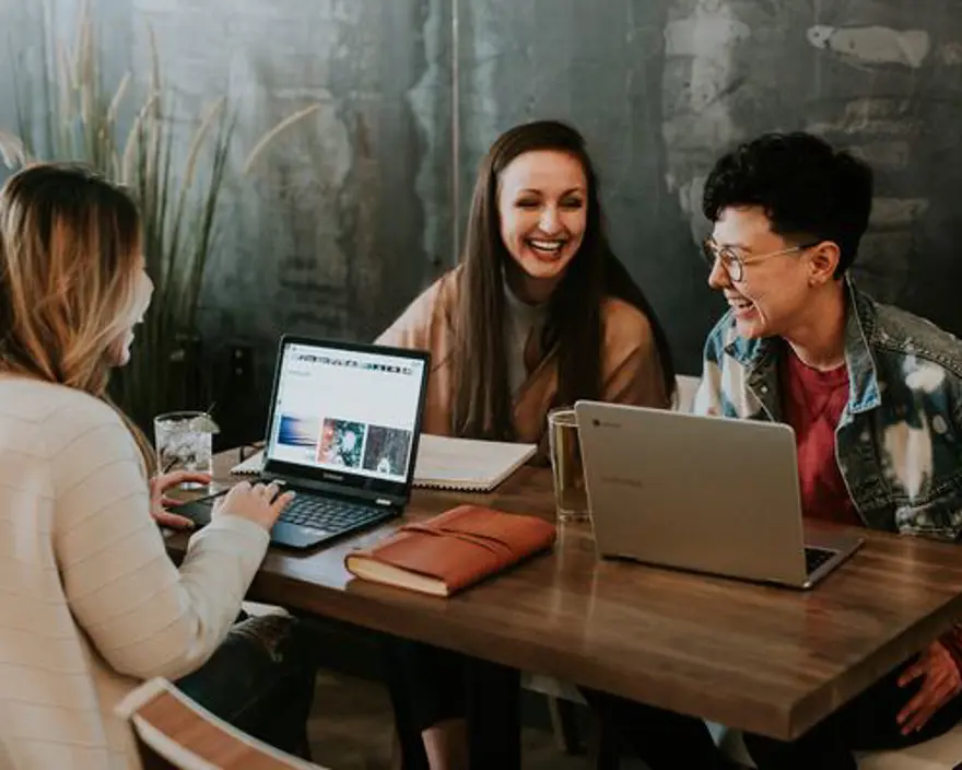 People at a table laughing around laptops.