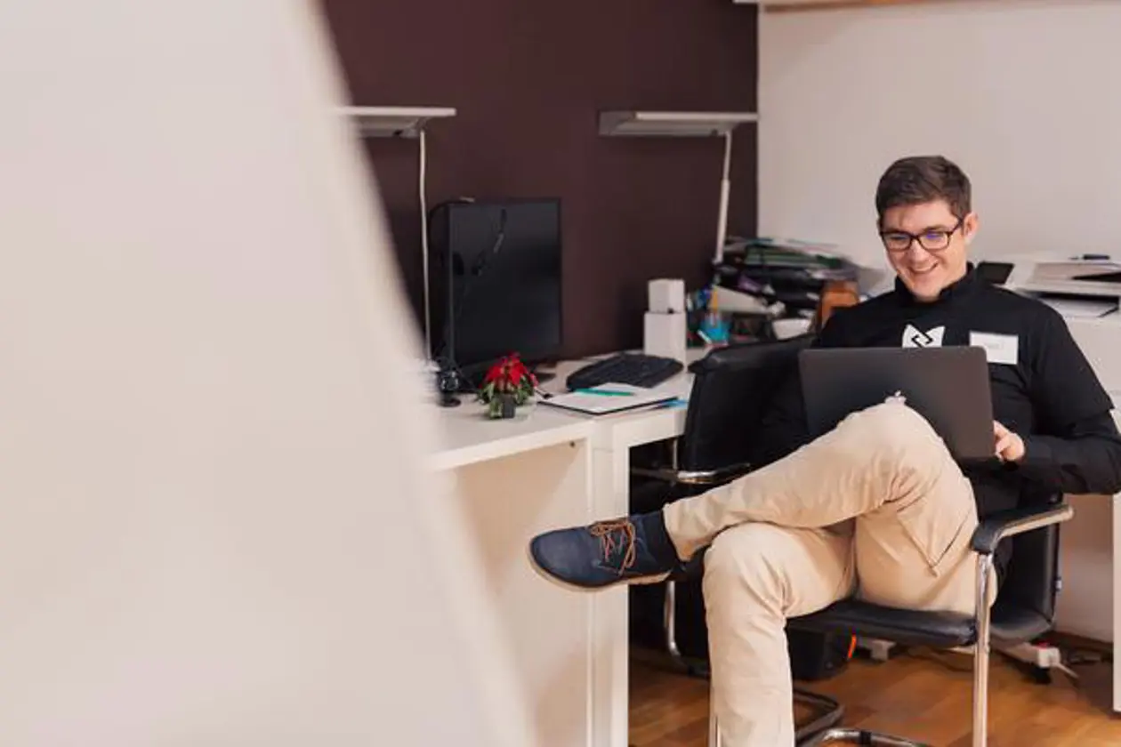 a man sitting in an office with his legs on a laptop
